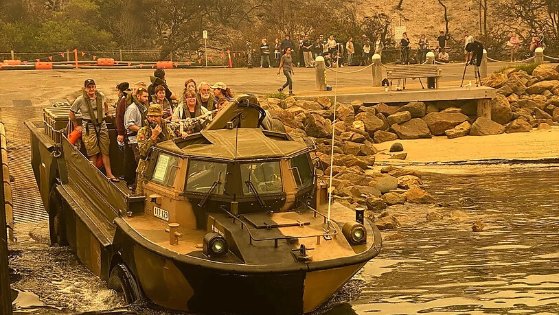 Menschen an der australischen Ostküste in der Kleinstadt Mallacoota werden mit Amphibienfahrzeugen des Militärs vor Buschfeuern in Sicherheit gebracht.