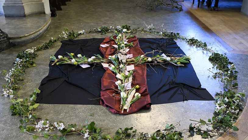Frisches Grün und Blütenzweige umfassen das Kreuz.