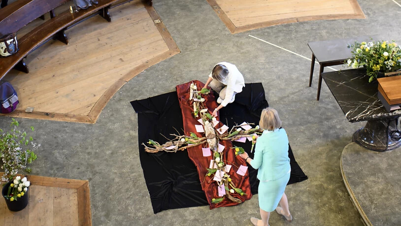 Ruhig und bedacht legen Barbara Rieder, Pfarrerin der Kirchgemeinde Heiliggeist und Irene Neubauer, Projektleiterin der offenen kirche bern die Blumen auf dem Kreuz aus.