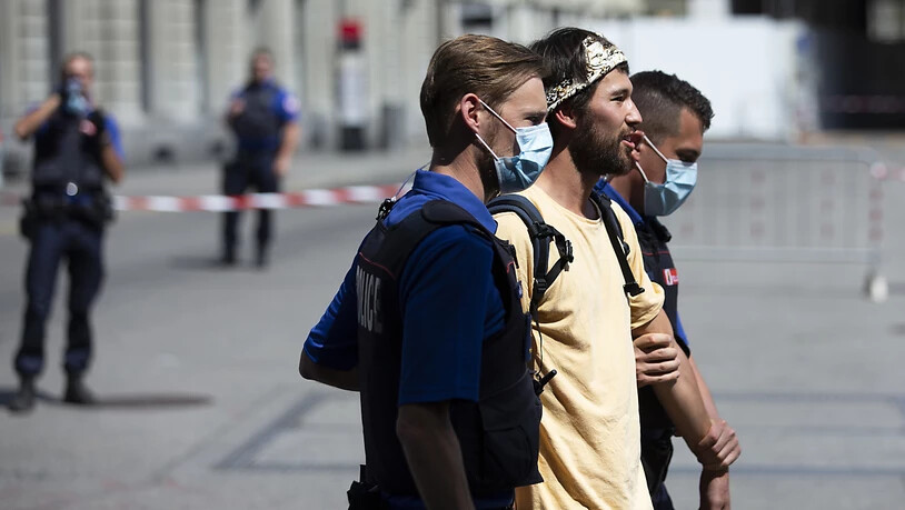 Maskierte Polizisten in Bern führen einen unmaskierten Demonstranten ab.