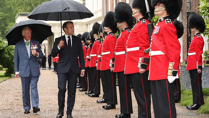 Der britische Prinz Charles (l), Prinz von Wales, und Emmanuel Macron (M), Präsident von Frankreich, gehen bei der Willkommenszeremonie die Grenadier-Garde im Clarence House ab. Foto: Jonathan Brady/PA Wire/dpa
