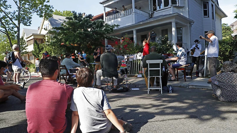 Menschen verfolgen die Veranstaltung «Make Music-New York». Aufgrund der Coronavirus-Pandemie traten verschiedene Musiker bei einem Freiluftkonzert auf, um für die Anwohner zu musizieren. Foto: Kathy Willens/AP/dpa