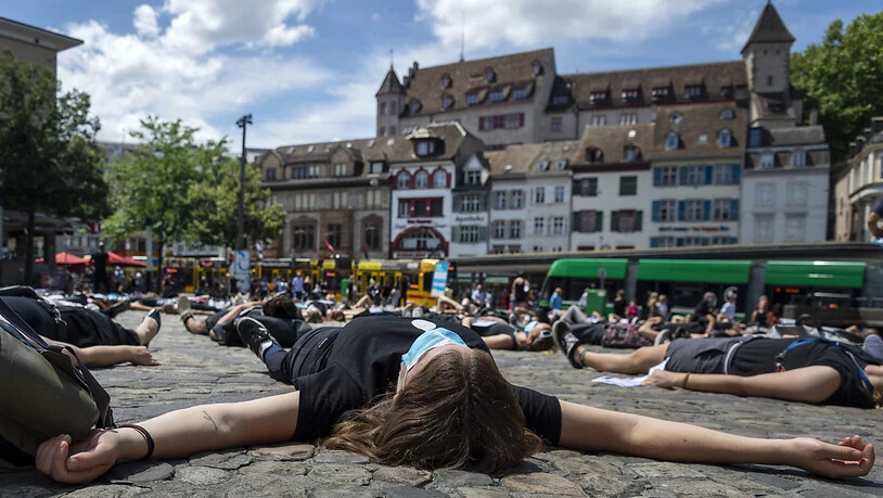 Teilnehmende einer Platzkundgebung gegen Rassismus in Basel legen sich auf dem Barfüsserplatz in Basel auf den Boden.