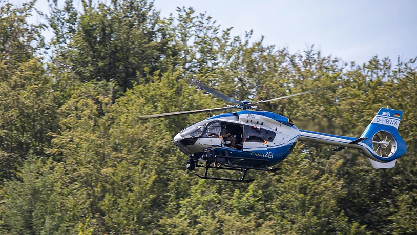 Ein Hubschrauber der Polizei fliegt nahe der Gemeinde Oppenau über den Wald. Die Polizei sucht mit einem Großaufgebot nach einem Mann, der am Sonntag, 12.07.2020 vier Polizisten bei einer Kontrolle in einer Hütte die Dienstwaffen abgenommen hatte. Foto:…