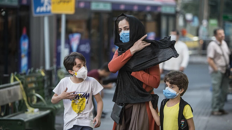 Kinder mit Gesichtsmasken gehen mit ihrer Mutter eine Straße entlang. Der Iran meldete am 21. Juli eine neue Rekordzahl an Corona-Toten. Foto: Ahmad Halabisaz/XinHua/dpa