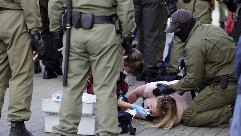 Eine Notärztin kümmert sich am Rande einer Demonstration gegen die Wahlergebnisse in Belarus um eine verletzte Frau, die neben Polizeibeamten auf dem Boden liegt. Foto: Uncredited/TUT.by/dpa