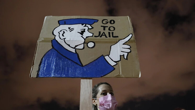 Eine Demonstrantin hält bei einem Protest in Tel Aviv ein Plakat in die Höhe. Foto: Ariel Schalit/AP/dpa
