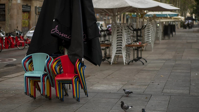 Stühle und Tische stapeln sich auf einer Bar-Terrasse in Barcelona. Foto: Emilio Morenatti/AP/dpa