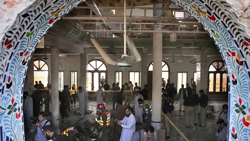 Rettungshelfer und Polizisten inspizieren den Ort in einer Koranschule, in der eine Explosion stattgefunden hat. Dabei sollen auch Kinder getötet und viele weitere Menschen verletzt worden sein. Foto: Muhammad Sajjad/AP/dpa