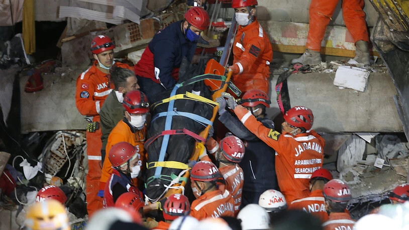 dpatopbilder - Rettungskräfte tragen ein Opfer aus den Trümmern eines eingestürzten Gebäudes. Ein starkes Erdbeben in der Ägäis hat in der Westtürkei und auf den griechischen Inseln für große Zerstörung gesorgt. Foto: Darko Bandic/AP/dpa