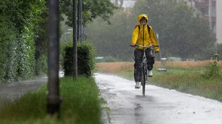 Nicht immer angenehm, aber gut für die Natur: Eine Velofahrerin pedalt in Chur durch den Regen. 