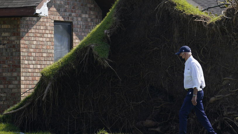 US-Präsident Joe Biden läuft an einem großen entwurzelten Baum vorbei, als er in LaPlace, Louisiana, selbst ein Bild von den Sturmschäden macht. Foto: Evan Vucci/AP/dpa