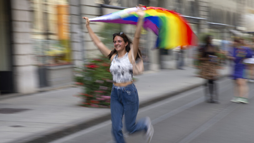 Teilnehmerin mit einer Regenbogen-Fahne an der Pride-Parade in der Genfer Innenstadt.