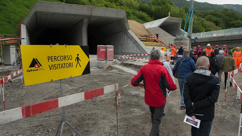 Besucher mit Schutzhelmen machen sich am Tunnelportal bereit für die Besichtigung im Ceneri Tunnel. (Archivbild)