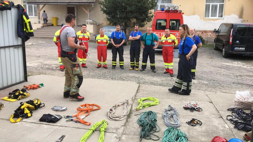 Instruktor Erwin Tschumi von der Feuerwehr Rapperswil-Jona gibt sein Wissen weiter, die lokalen Feuerwehrleute hören in ihren unterschiedlichen, gespendenten Einsatzkleidern aufmerksam zu.