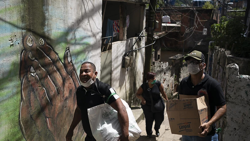 Freiwillige bringen Pakete mit Seife und Waschmittel in einen Slum in Rio de Janeiro.