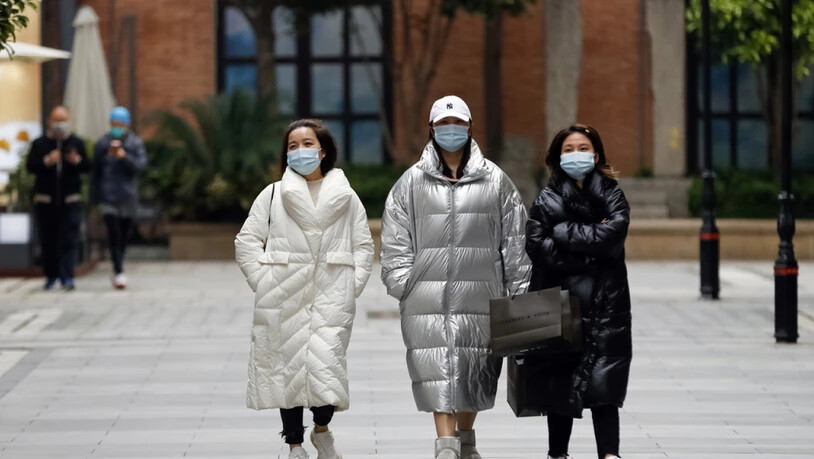 Passanten am Montag in Wuhan, wo die Pandemie ihren Ausgang nahm. Auch Experten fragen sich, warum die Corona-Zahlen aus China eher niedrig sind.
