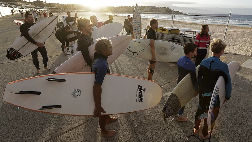 Surferinnen und Surfer warten auf die Öffnung des Bondi Beach in Sydney. Dort darf wieder Sport getrieben werden.