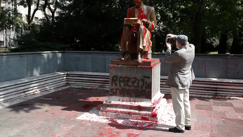 Ein Mann fotografiert die von Demonstranten mit roter Farbe beworfene Statue des verstorbenen italienischen Journalisten Indro Montanelli in Mailand. Foto: Antonio Calanni/AP/dpa
