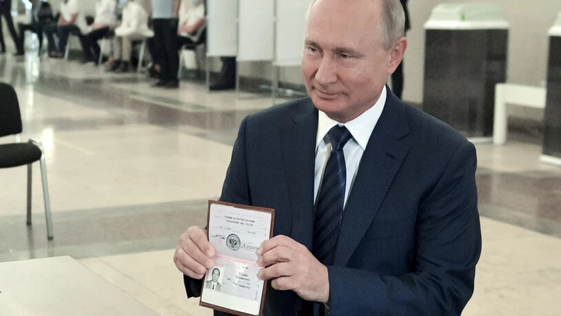 Wladimir Putin, Präsident von Russland, zeigt einer Mitarbeiterin der Wahlkommission seinen Pass in einem Wahllokal. Foto: Alexei Druzhinin/Pool Sputnik Kremlin/AP/dpa