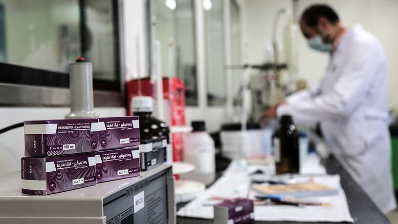 ARCHIV - Ein Mitarbeiter des ägyptischen Pharmaunternehmens «Eva Pharma» arbeitet an der Produktion des Wirkstoffs Remdesivir, einem antiviralen Breitspektrum-Medikament, während Packungen des Medikaments neben ihm liegen. Foto: Fadel Dawood/dpa