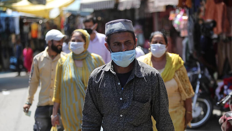 Passanten gehen mit Mundschutz über einen Markt in Jammu. Foto: Channi Anand/AP/dpa