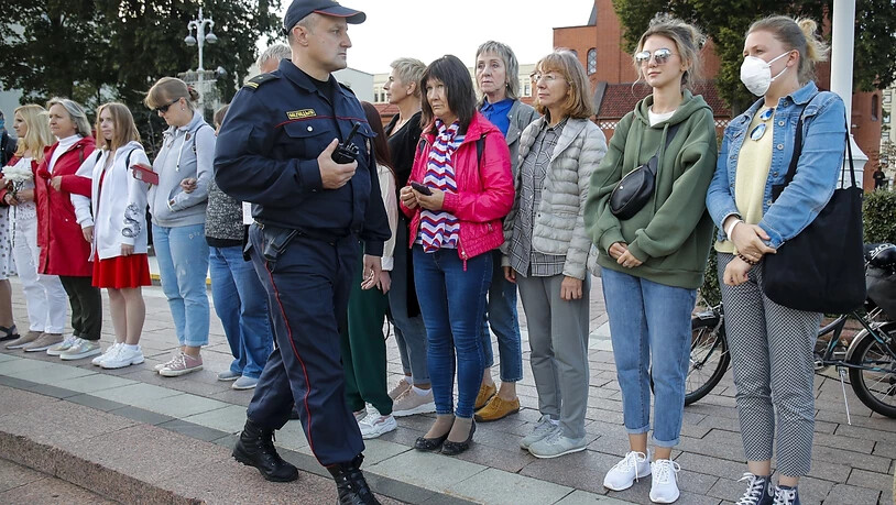 Ein Polizist bittet Demonstrantinnen in Minsk, den Ort zu verlassen. Foto: Dmitri Lovetsky/AP/dpa
