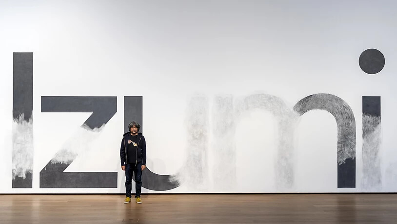 Taro Izumi vor seiner von ihm und seinem Team bearbeiteten Ankündigungswand im Museum Tinguely Basel.