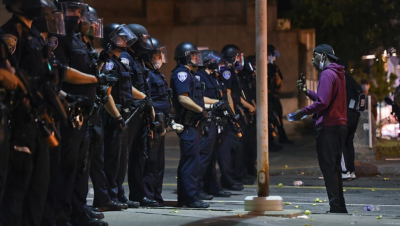 Ein Demonstrant steht während einer Demonstration vor Polizisten. Nachdem ein 41-jähriger Afroamerikaner infolge eines brutalen Polizeieinsatzes verstarb, wurden sieben Beamte vom Dienst suspendiert. Foto: Adrian Kraus/AP/dpa