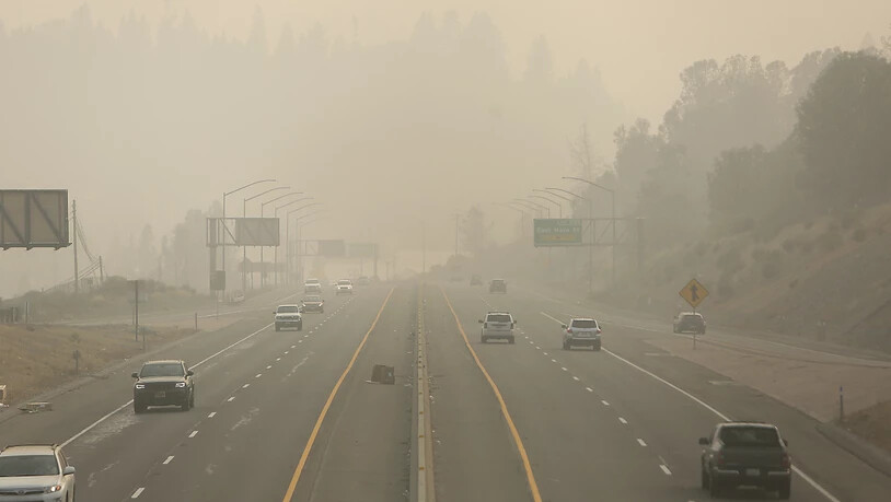 Autos fahren auf der Golden Center Autobahn durch dichten Rauch, der sich von den Waldbränden an der Westküste der USA ausbreitet. Foto: Elias Funez/The Union/AP/dpa - ACHTUNG: Nur zur redaktionellen Verwendung und nur mit vollständiger Nennung des…