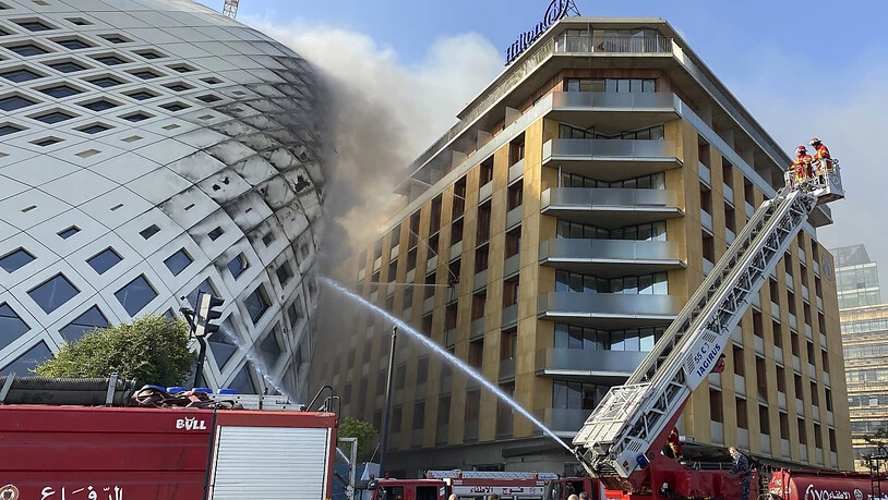 Feuerwehrleute löschen einen Brand im Geschäftsviertel der libanesischen Hauptstadt. Betroffen ist das sich noch im Bau befindlichen Gebäude (l), das von der Architektin Zaha Hadid entworfen wurde. Foto: Fadi Tawil/AP/dpa