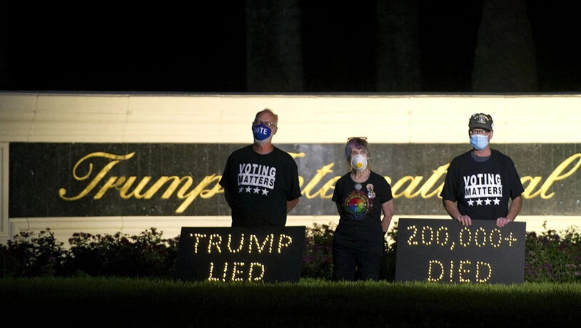 Die Demonstranten Mark Beaumont (l-r), Joyce Brown und Bruce Brown halten in der Nähe des Trump International Golf Club eine Mahnwache ab. In den USA sind inzwischen fast 200 000 Menschen nach einer Corona-Infektion gestorben. Foto: Meghan Mccarthy/Palm…