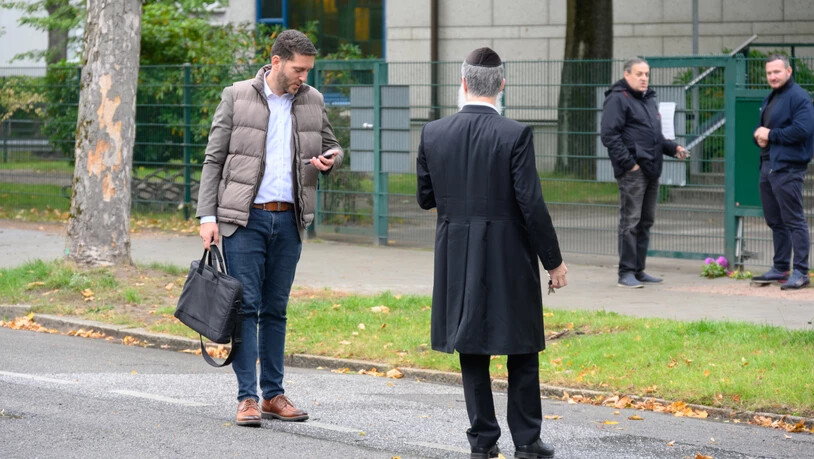 Philipp Stricharz (l), erster Vorsitzender der jüdischen Gemeinde Hamburg, steht mit Shlomo Bistritzky, Landesrabbiner von Hamburg, vor der Synagoge und schaut auf sein Handy. Ein Mann im Tarnanzug hatte einen Studenten mit einem Spaten angegriffen. Foto…