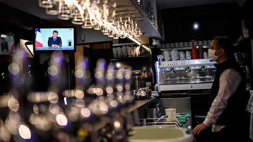 Emmanuel Macron, Präsident von Frankreich, ist auf einem Bildschirm eines Fernsehers in einem Café zu sehen. Foto: Christophe Simon/AFP/dpa
