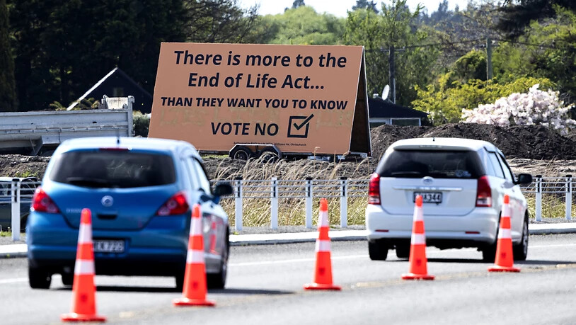 ARCHIV - Autos fahren auf einer Straße an einem Plakat vorbei, das Wähler dazu auffordert, mit «Nein» gegen Euthanasie zu stimmen. Die Bürger Neuseelands haben sich in einem Referendum jedoch für die Legalisierung der Sterbehilfe in dem Pazifikstaat…