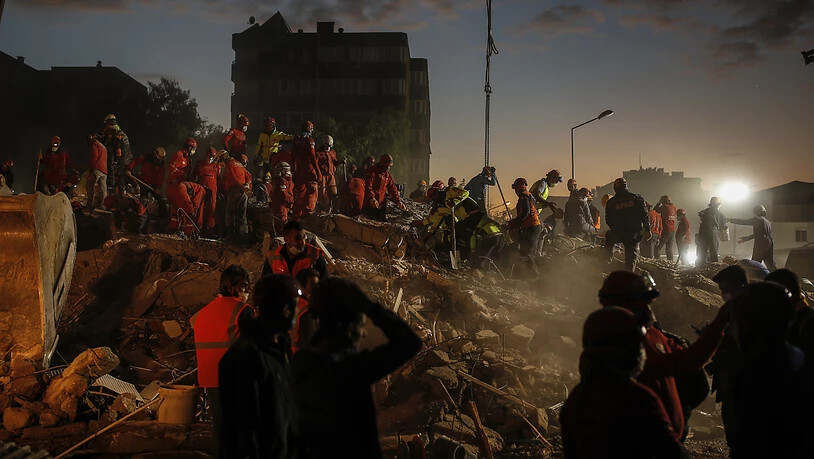 Mitglieder des Rettungsdienstes suchen in den Trümmern eines eingestürzten Gebäudes in Izmir nach Überlebenden. Foto: Darko Bandic/AP/dpa