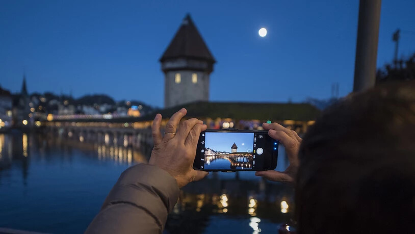 Eine asiatische Touristin macht ein Foto der Kapellbruecke mit dem Smartphone in der Altstadt von Luzern. (Archivbild)
