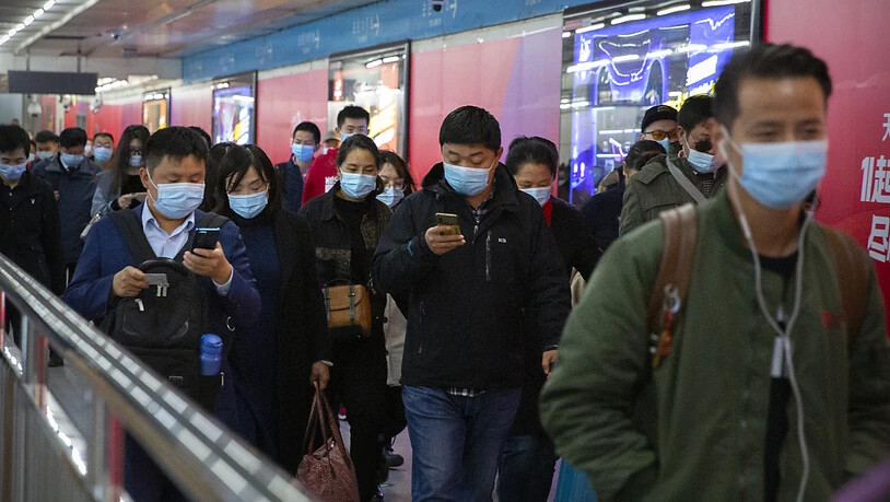 ARCHIV - Pendler schauen auf ihre Smartphones, während sie durch eine U-Bahn-Station in Peking gehen. Gut ein Jahr nach dem Ausbruch gilt das Coronavirus in China als so gut wie besiegt. Selbst in der besonders betroffenen Metropole Wuhan ist von Krise…