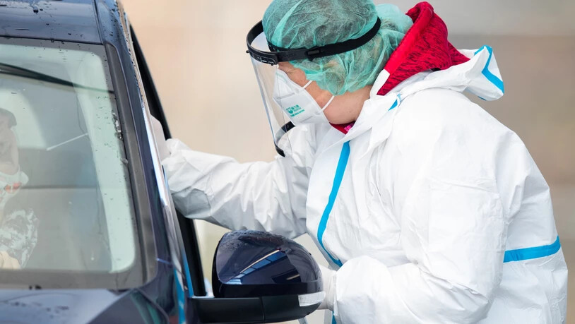 Eine Mitarbeiterin macht in einem Corona-Abstrich-Zentrum bei einem Autofahrer einen Abstrich für einen Corona-Test. Foto: Tom Weller/dpa