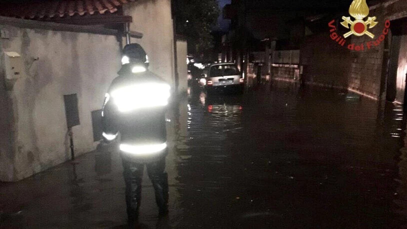 HANDOUT - Ein Feuerwehrmann steht in einer überfluteten Straße auf Sardinien. Auf der italienischen Mittelmeerinsel hat ein Unwetter schwere Schäden angerichtet. Foto: Vigili del Fuoco/dpa - ACHTUNG: Nur zur redaktionellen Verwendung im Zusammenhang mit…