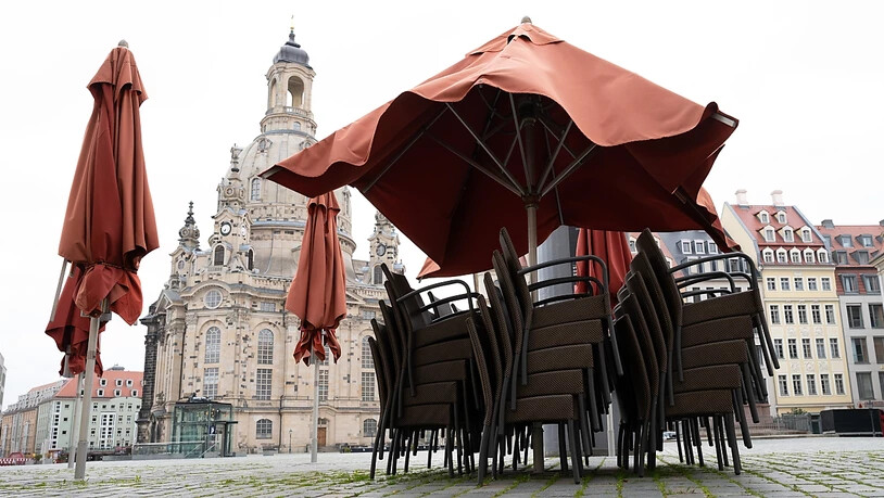 Leere Stühle stapeln sich vor einem Restaurant auf dem Neumarkt vor der Dresdener Frauenkirche. Die Menschen in Deutschland müssen sich ab dem Wochenende auf neue Corona-Beschränkungen einstellen. Foto: Sebastian Kahnert/dpa-Zentralbild/dpa