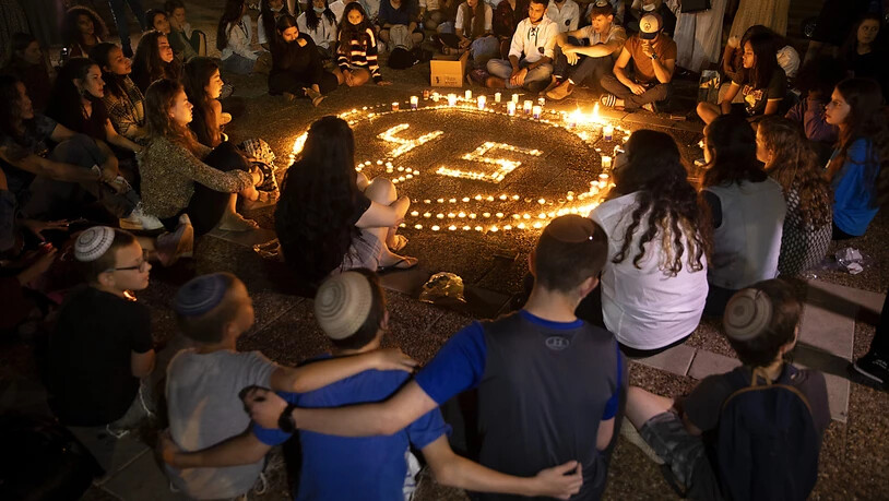 ARCHIV - Menschen sitzen während einer Mahnwache um einen Kreis von Kerzen zum Gedenken an die 45 Opfer, die bei einer Massenpanik an einem Wallfahrtsort ums Leben gekommen sind. Nach der Polizei will auch der sogenannte Staatskontrolleur in Israel das…