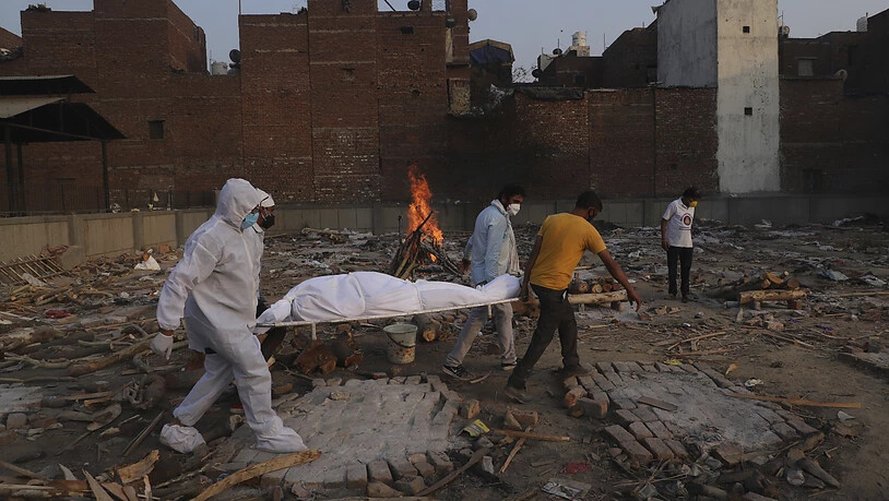 Personen tragen einen Toten in Neu Delhi auf einer Trage zur Einäscherung. Foto: Amit Sharma/AP/dpa