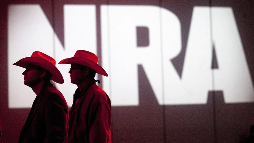 ARCHIV - Zwei Personen gehen an einem Schriftzug der NRA vorbei. Foto: Johnny Hanson/Houston Chronicle/AP/dpa - ACHTUNG: Nur zur redaktionellen Verwendung und nur mit vollständiger Nennung des vorstehenden Credits