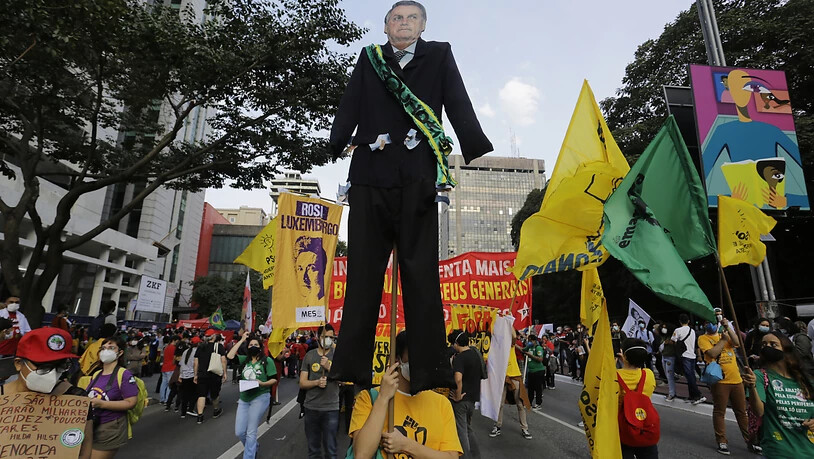 Menschen, die an einem Marsch auf der Avenida Paulista teil, um den Rücktritt des brasilianischen Präsidenten Jair Bolsonaro zu fordern, tragen einen riesigen Ausschnitt von Bolsonaro. Foto: Nelson Antoine/AP/dpa