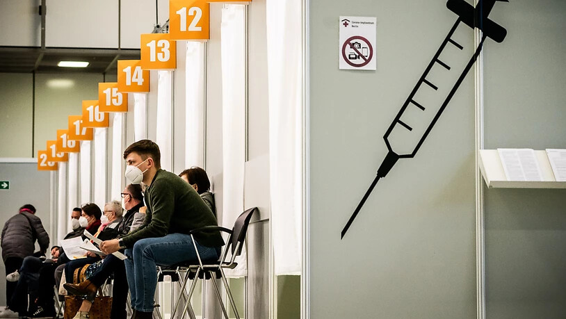 ARCHIV - Menschen warten im Corona-Impfzentrum auf dem Messegelände in Berlin auf ihre Impfung. Foto: Michael Kappeler/dpa