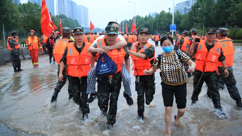 Mitarbeiter des Militärs tragen Patienten eines Krankenhauses über eine überschwemmte Straße. Laut Angaben des chinesische Staatsfernsehens am Freitag ist die Zahl der Toten nach den schweren Überschwemmungen in der chinesischen Metropole Zhengzhou auf…