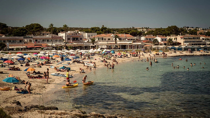 Urlauber kühlen sich am Strand Punta Prima auf Menorca ab. Die Corona-Zahlen sind in großen Teilen Spaniens rapide angestiegen. Deshalb stuft die deutsche Regierung laut Angaben des Robert Koch-Instituts Spanien von Dienstag an als Corona…