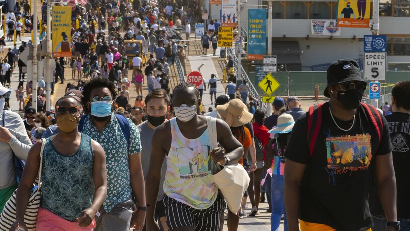ARCHIV - Menschen drängen sich am Santa Monica Pier. In den USA nimmt die Zahl der an einem Tag erfassten Corona-Neuinfektionen wieder zu. Foto: Damian Dovarganes/AP/dpa