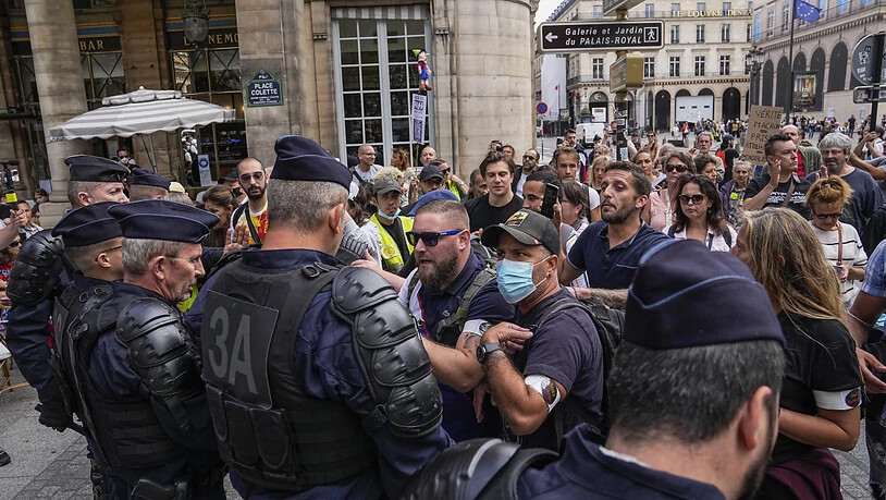 Demonstranten stehen bei einem Protest gegen den neuen Gesundheitspass in Paris Polizisten gegenüber. Foto: Michel Euler/AP/dpa